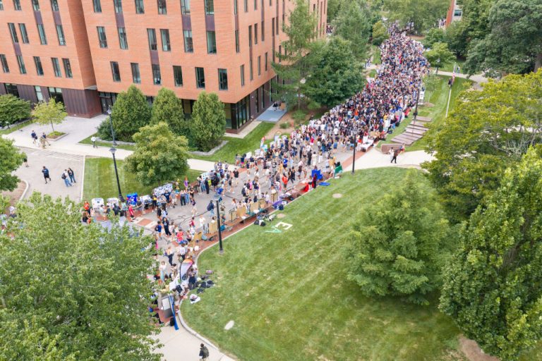Aerial view of a large crowd of students gathered along a walkway on the UConn campus. 