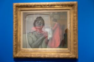 "Marie" by Ray DiCapua reflects off the glass of the frame containing "La Robe de Chambre Rouge 