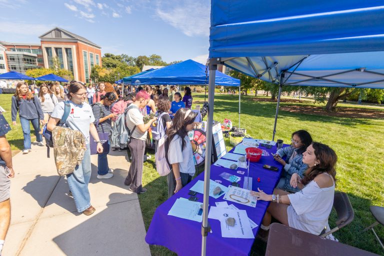 A long line of students looks at booths set out on the Student Union lawn for the Health and Wellness Fair.