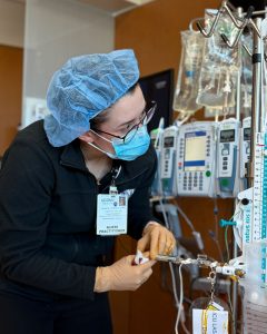 female nurse practitioner in personal protective equipment in patient room