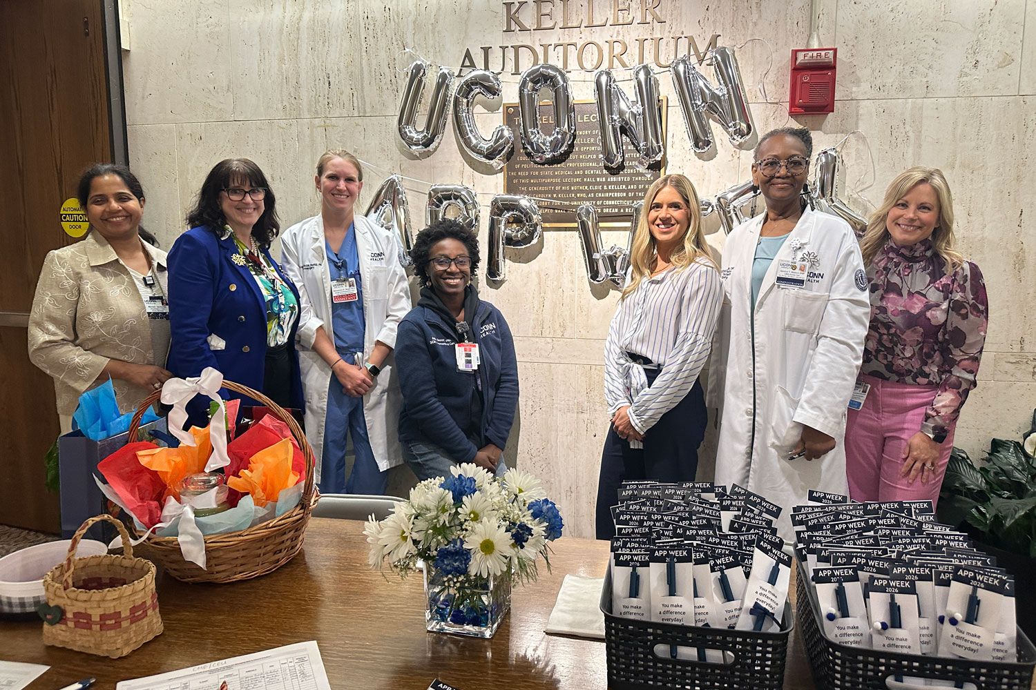 group portrait of seven women indoors in front of ballons spelling out "UConn APP Week"