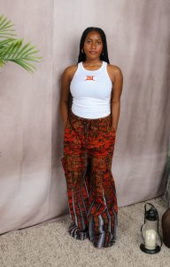 A woman standing in a white tank top and red and black pants