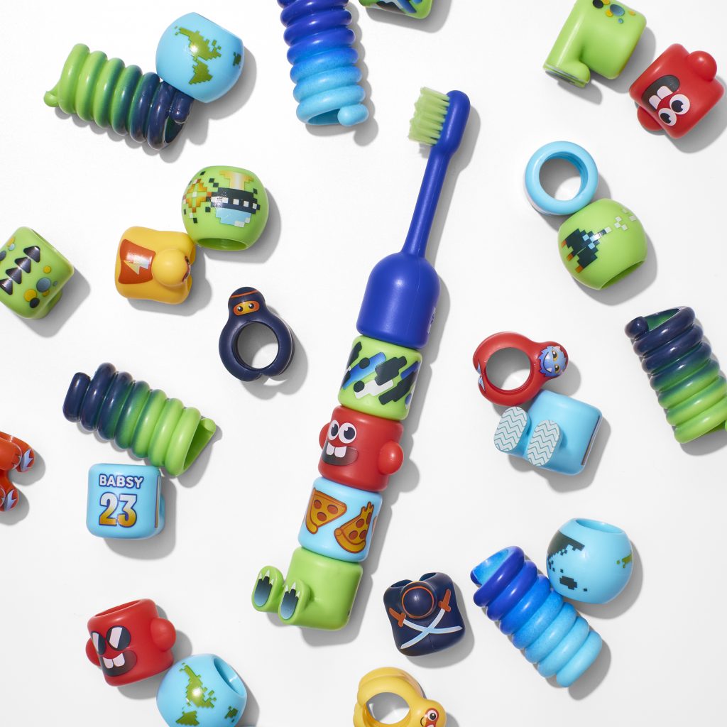 A child's toothbrush surrounded by detachable elements that can be added to or subtracted from the brush.