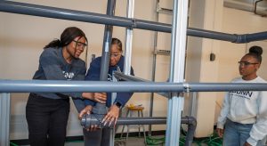 Three female students building laboratory equipment.