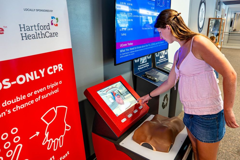 Female student interacts with the CPR kiosk