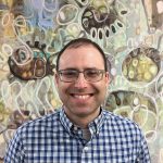 Man smiling with glasses in front of pattern