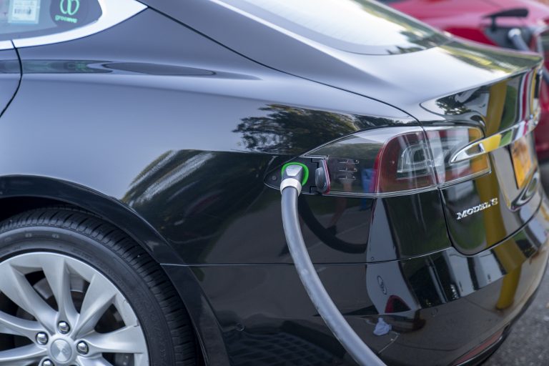 A Tesla electric car recharges its batteries at a gas and charging station.