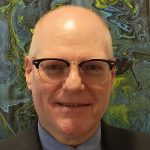 Man smiling with glasses in suit