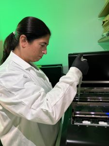 A scientist uses a pipette to move genetic material into a sequencing machine