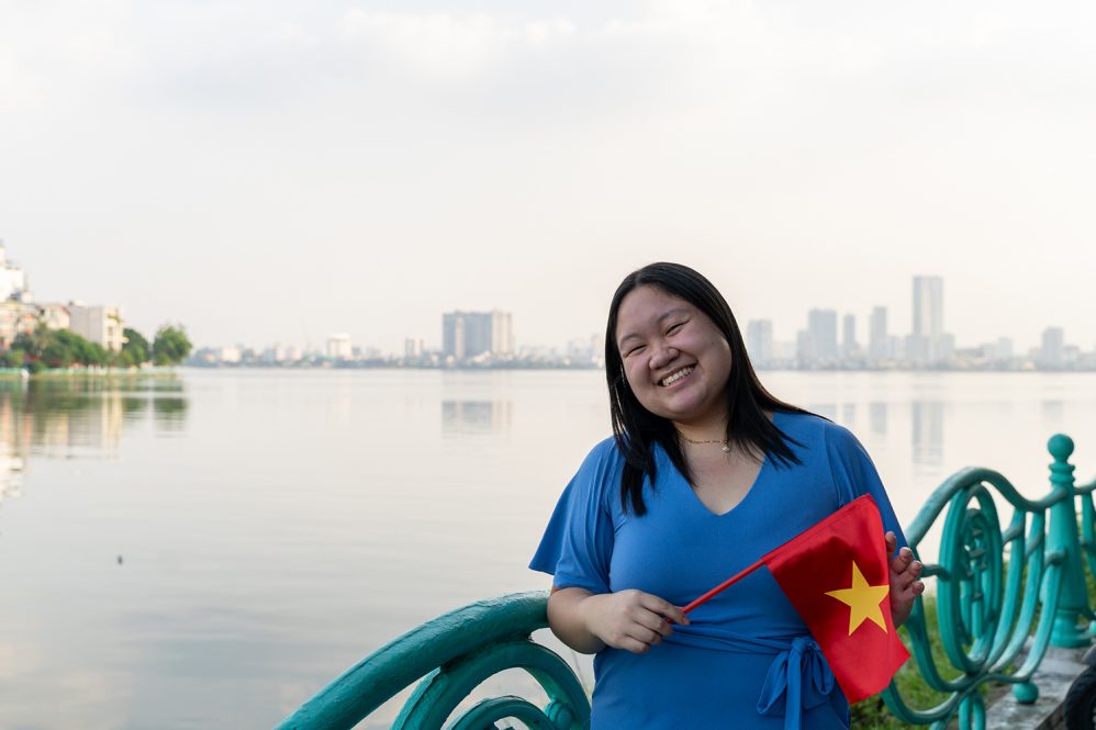 Lynna Vo poses outside while holding the Vietnamese flag in Vietnam.