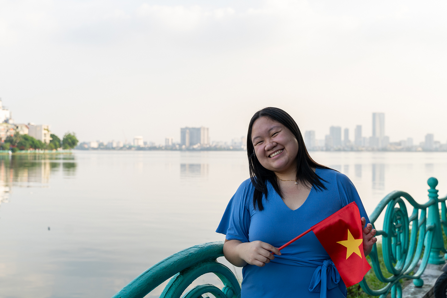 Lynna Vo poses outside while holding the Vietnamese flag in Vietnam.