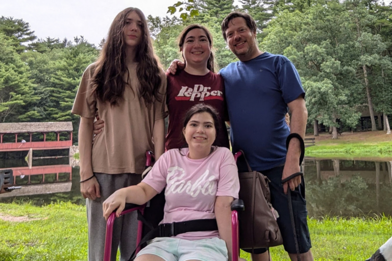 a girl in a wheelchair with two men and a woman standing behind her