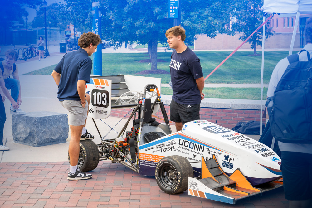Two male students looking at formula 1 racing car