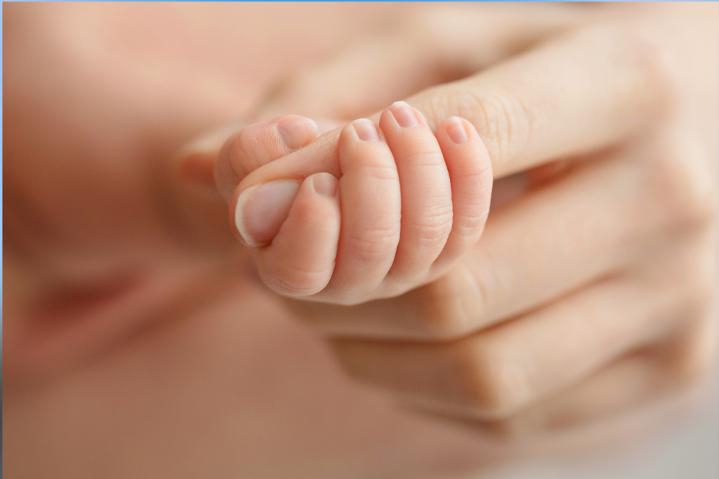 a baby hand wrapped around an adult finger