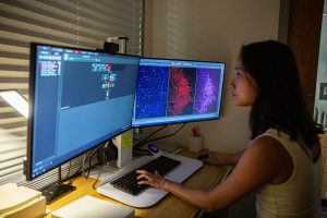 A researcher sitting at a computer examining brightly colored representations of neural activity