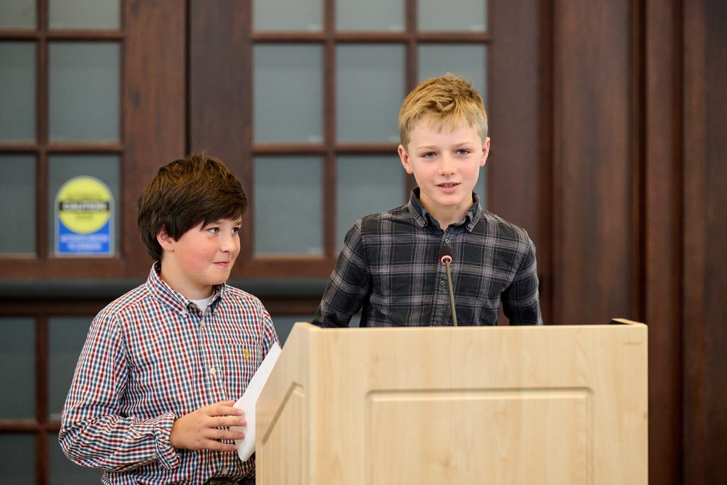 Two young boys stand at podium