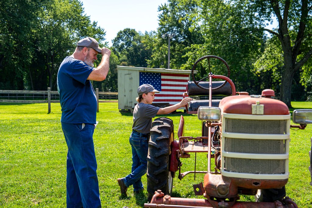 Older man and young boy work on a tractor