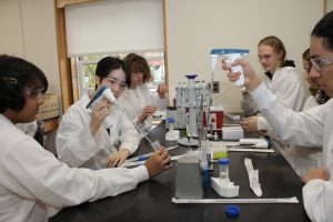 Students in labcoats work with pipetting equipment