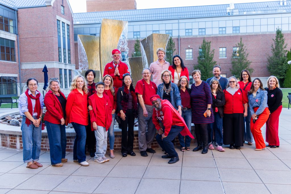 A group of people in matching red shirts pose for a photo in front of a fountain.