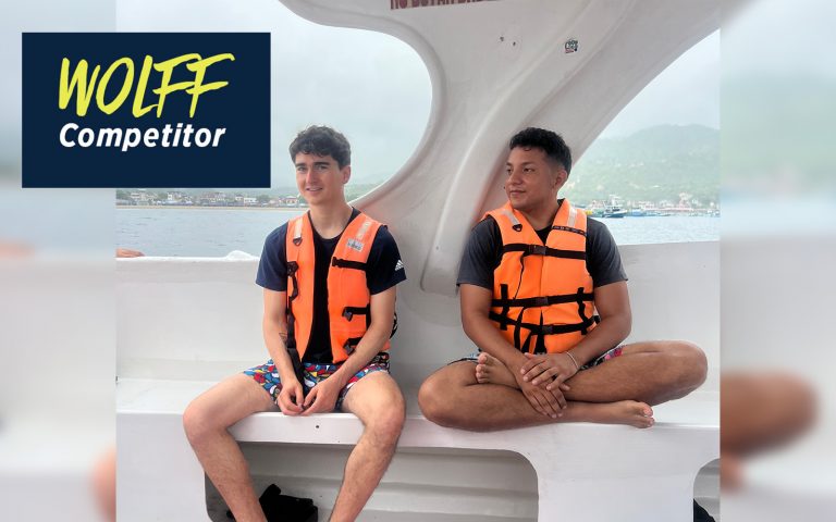 Two men wearing life jackets sit next to each other on a boat.