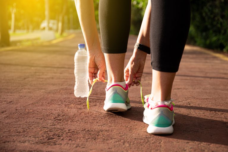 A woman reaching down to lace up a pair of running shoes