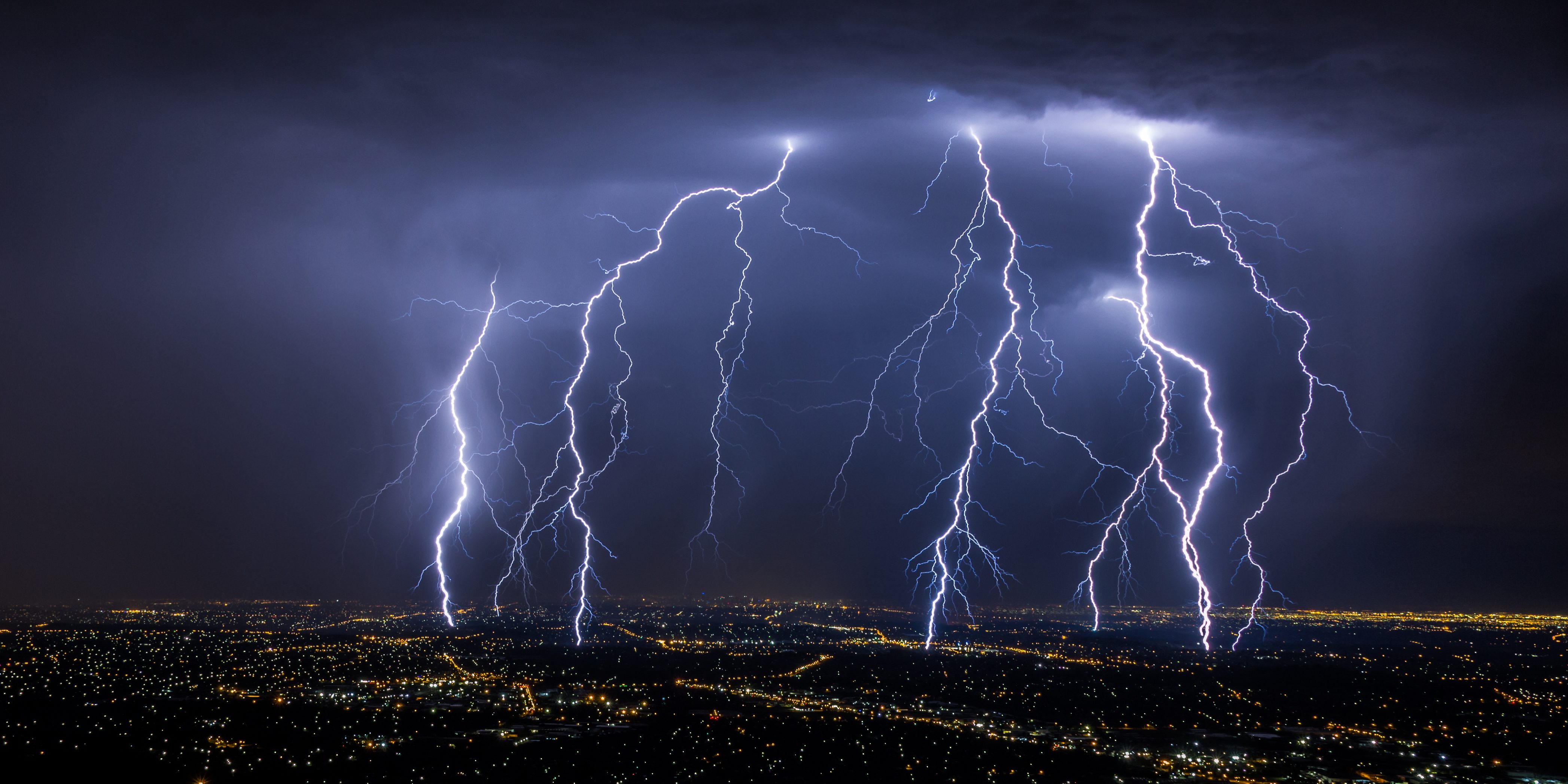 Lightning strikes over a city at night, illustrating the sudden and dangerous nature of so-called cytokine storms, potentially fatal episodes where inflammation-causing proteins flood the blood.